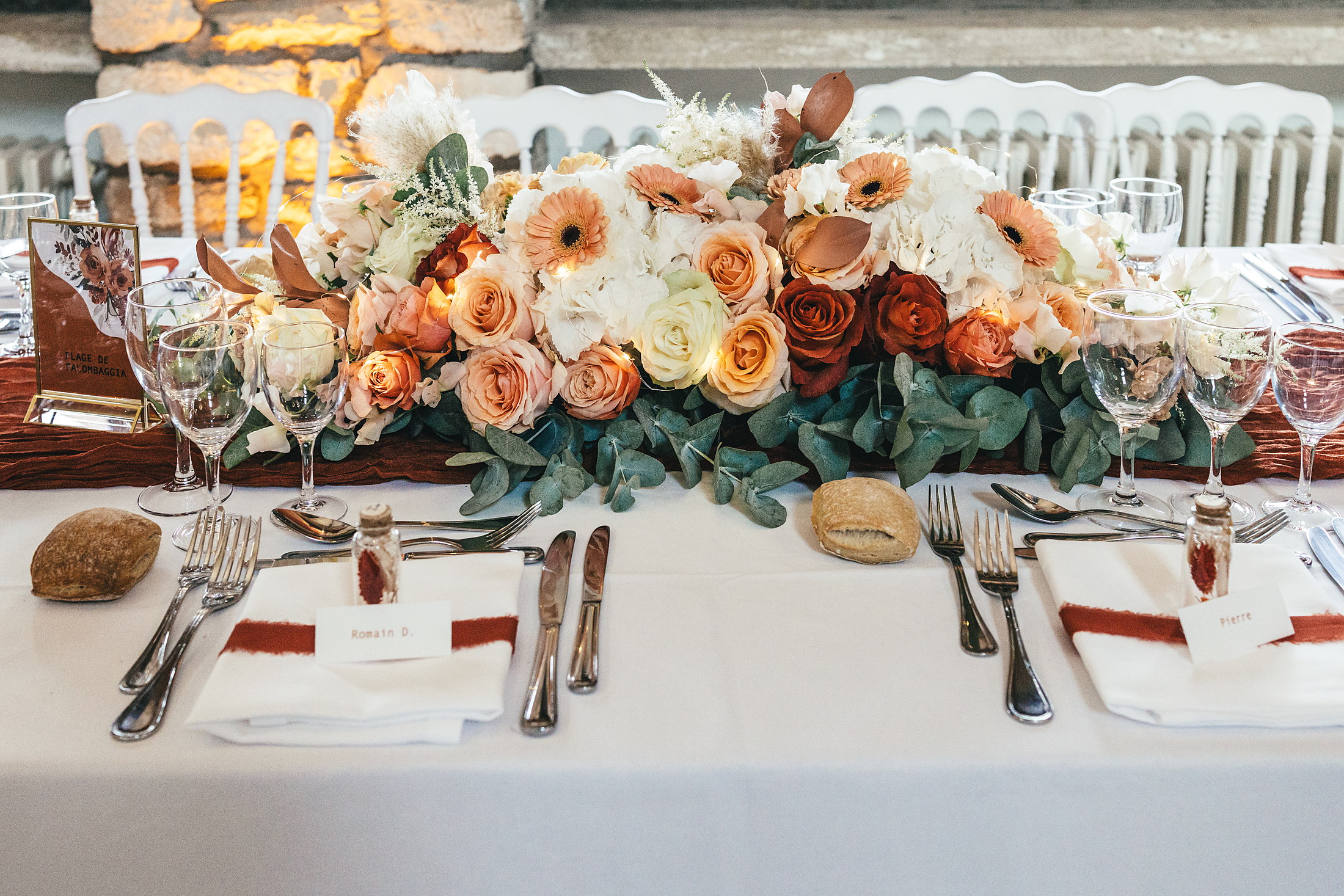 Centre de table fleuri aux tons sunset du dîner de mariage