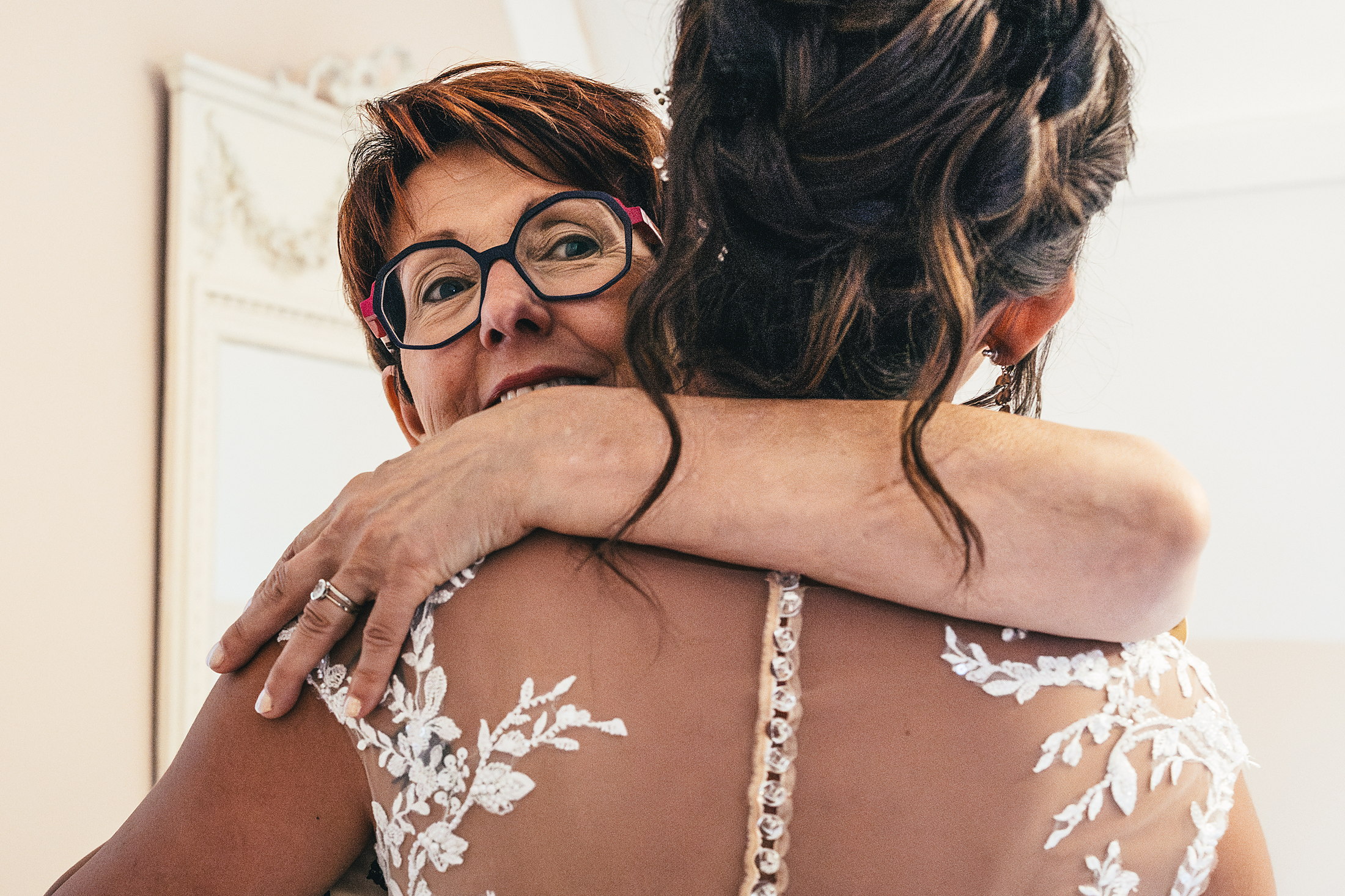 La maman de la mariée émue dans les bras de sa fille en robe de mariée