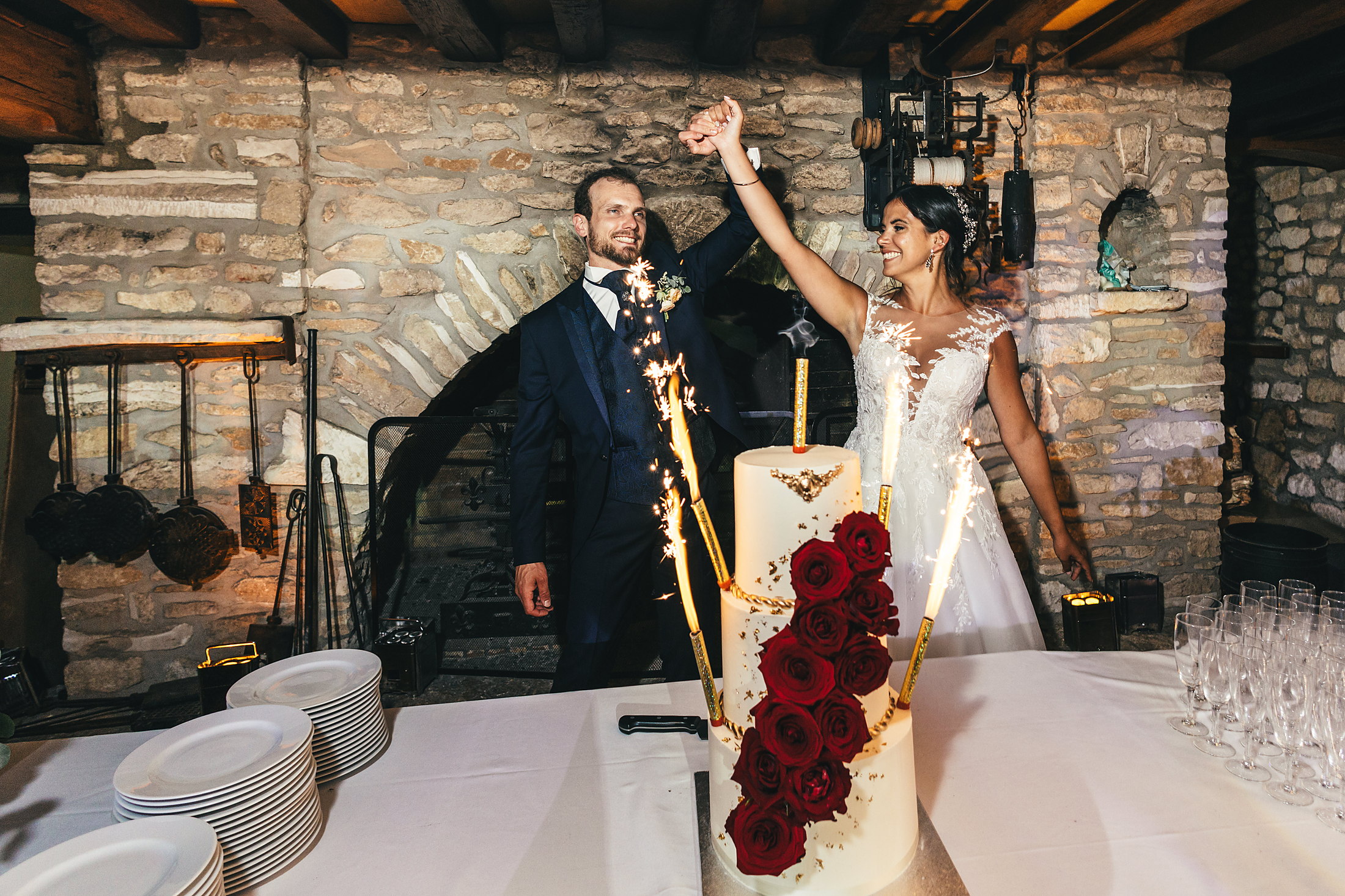 Les mariés présentent le wedding cake aux roses rouges sous les cierges magiques